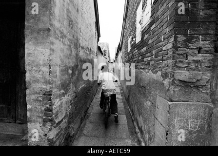 Ein Junge in einem sehr engen Peking Hutong 2003 Radfahren Stockfoto