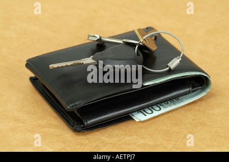 Brieftasche mit Banknoten von hundert Euro und Schlüsselanhänger mit Schlüssel auf gelbem Hintergrund Stockfoto