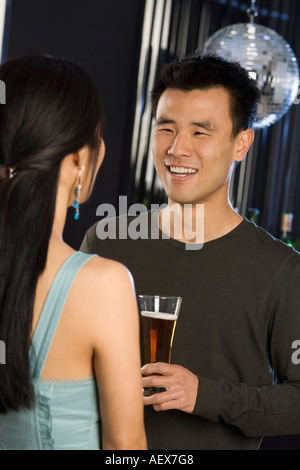 Mann mit Bier im Gespräch mit Frau in Nachtclub Stockfoto