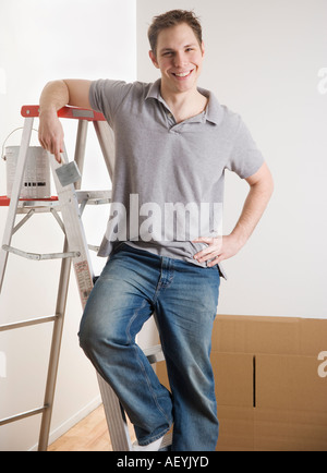Man stützte sich auf Leiter mit Farbe im Innenbereich Stockfoto