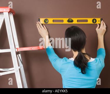 Frau mit Niveau an Wand Stockfoto