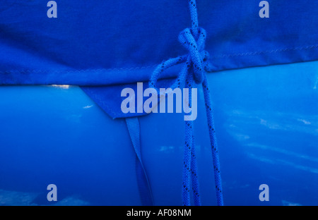 Detail der dunkle blaue Plane erstreckte sich über Mittelblau Rumpf des Bootes mit verknotet Mitte blaues Seil halbiert Bild Stockfoto