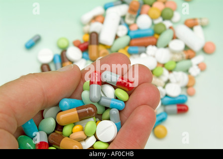 Hand voll Pillen in verschiedenen Farben und Formen im Hintergrund mehr Pillen Stockfoto