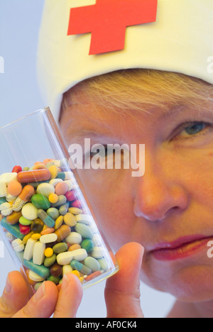 Glas gefüllt mit Pillen in verschiedenen Farben und Formen in der Hand einer Krankenschwester Stockfoto