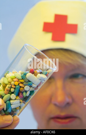 Glas gefüllt mit Pillen in verschiedenen Farben und Formen in der Hand einer Krankenschwester Stockfoto