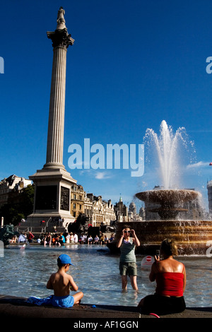 Eine Familie genießt die Sommersonne beim Abkühlen von den Springbrunnen nahe Trafalgar Square. Stockfoto