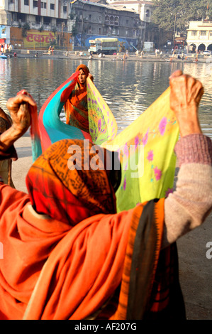 Indische Frauen halten Saris, um im Sonnenschein am Ramkund Badebecken, Nasik, Maharashtra, Indien auszutrocknen Stockfoto