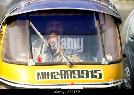 Auto-Rikscha-Fahrer guckend durch Windschutzscheibe, während im Verkehr sitzen, Pune, Indien Stockfoto