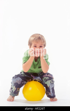 Junge sitzt auf ball Stockfoto