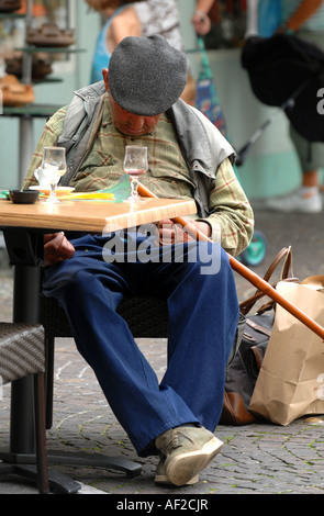 Französischer Mann schlafend an einem Cafétisch mit einem leeren Glas Wein vor ihm, Frankreich Stockfoto