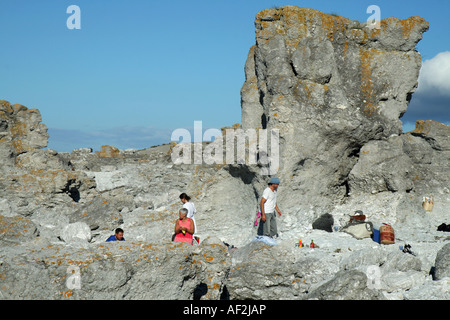 Touristen, die mit einem Picknick unter den Seastacks genannt Rauks, in Fårö-Gotland. Diese sind auf Digerhuvud. Stockfoto