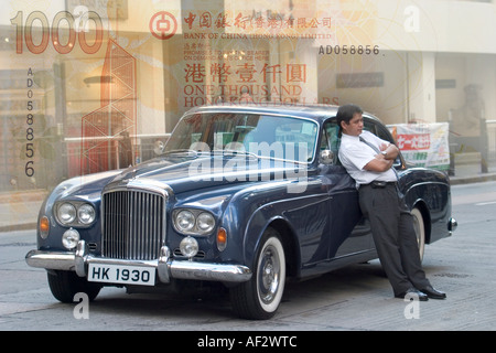 Alte antike Bentley mit Chauffeur stehen gegen Fahrer Auto Hongkong $1000 Geld Zusammensetzung Montage Konzept Geld Reichtum Stockfoto