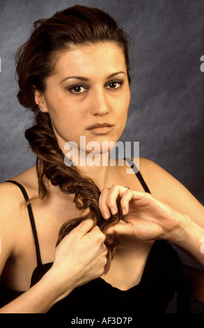 Porträt einer jungen Frau, nachdenklich zu spielen mit ihren langen Haaren, Deutschland Stockfoto