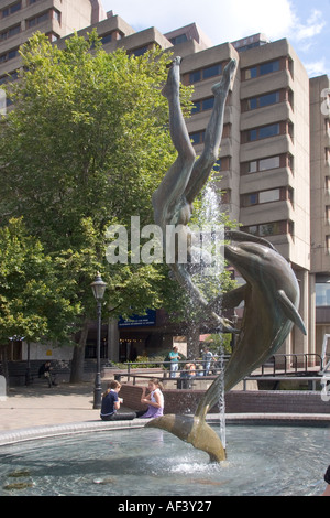 Mädchen spielen mit Dolphin Statue und Brunnen in der Nähe von Tower Bridge mit Tower Hotel im Hintergrund Stockfoto