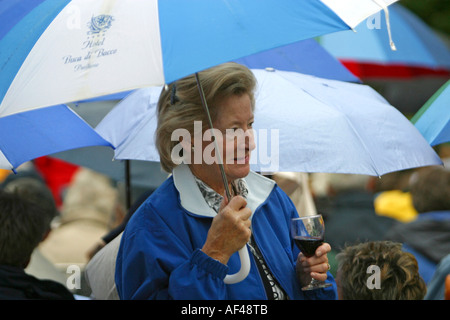 Eine Frau trinkt ein Glas Wein unter einem Regenschirm bei einem Picknick im alten Pfarrhaus vor einer Opernaufführung Stockfoto