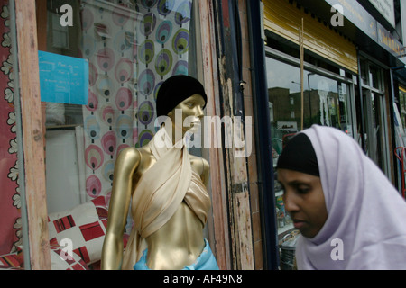 Eine somalische Einwanderer Frau geht vorbei an einer Puppe in einem Schaufenster Finsbury Park London Stockfoto