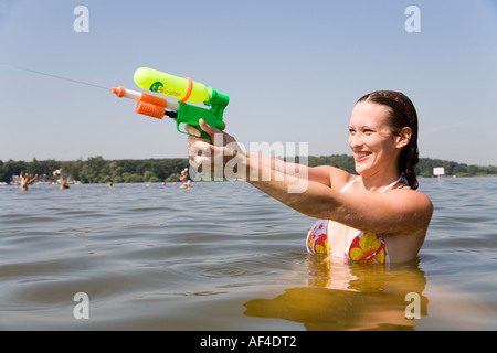 Junge Frau (30) mit einer Pumpe Pistole im See, Badestrand Wannsee, Berlin Stockfoto