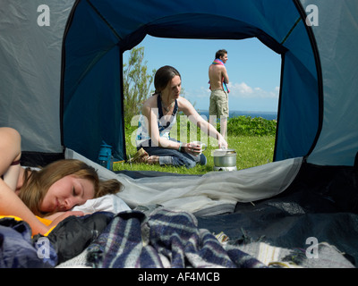 Blick durchs Zelt mit jungen weiblichen Inneren zu öffnen, während ein anderes mit einem jungen männlichen stehen außerhalb kocht Stockfoto