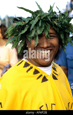 Lächelnd Tahitian Mann in traditioneller Kleidung tragen leuchtend gelben Poncho und grünen Kopfschmuck auf dem Pacific Arts Festival Stockfoto