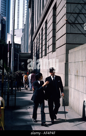 Englischen Stadt Gent in Melone Ende der 1970er Jahre zu Fuß mit chinesischen Mann sowohl in Anzügen im Central District Street in Hong Kong Stockfoto