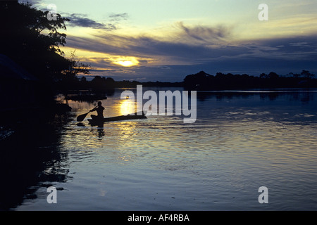 Lokaler Mann Paddel Kanu gegen den Sonnenuntergang über den Fluss und Landschaft Silhouette Regenwald im Amazonasgebiet von Brasilien Stockfoto