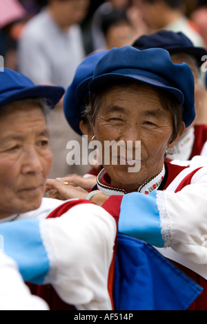 Naxi chinesische Frauen in traditionellen Kostümen tanzen in Markt-Platz, Altstadt von Lijiang, Yunnan Provinz, China Stockfoto