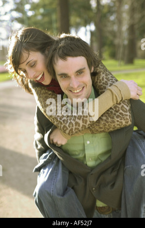 Junge Frau Reiten Huckepack auf einem jungen Mann Stockfoto