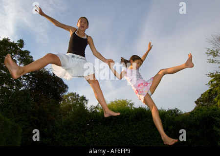 Horizontale Porträt zweier Mädchen in der Luft Spaß springen auf einem Trampolin im Garten. Stockfoto