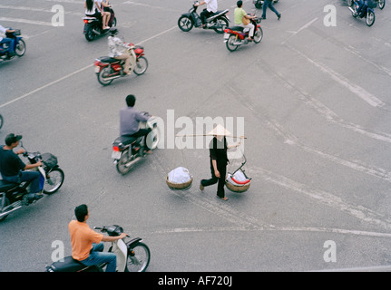 Konische Hut tragen Frau, die Essen in der Altstadt von Hanoi in Vietnam in Fernost Südostasien. Die Leute auf der Straße beobachten Urban Reportage Besetzung Stockfoto