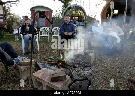 Reisende, Zigeuner und ihre Freunde sitzen um ein Lagerfeuer neben traditionellen Wohnwagen in Kent im Jahr 2005 Stockfoto