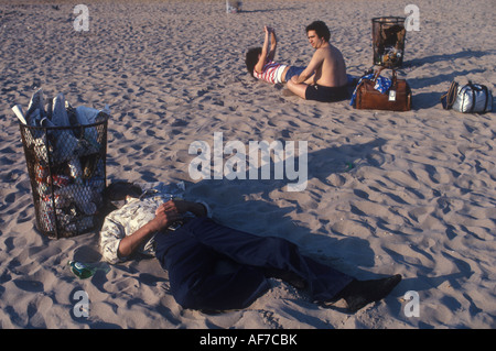 Betrunkener Mann schläft am Strand neben einem Abfalleimer Coney Island 1980s 1981 Brooklyn, New York City USA HOMER SYKES Stockfoto