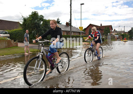 Zwei Frauen, Radfahren durch Überschwemmungen im Bereich Longford von Gloucester in England Juli 2007 nach einem schweren Hochwasser Stockfoto