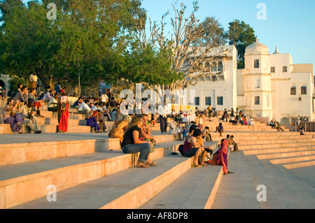 Horizontale Ansicht von Touristen und lokalen Indianer sitzen zusammen auf den Ghats am See beobachten Sie den Sonnenuntergang in Pushkar. Stockfoto