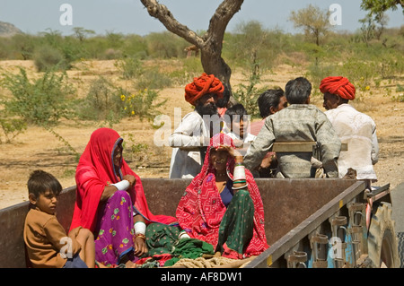 Horizontale erhöhten Blick auf traditionell gekleideten Rajasthanis Landarbeiter einen Aufzug auf der Rückseite eines Traktors zu trampen. Stockfoto