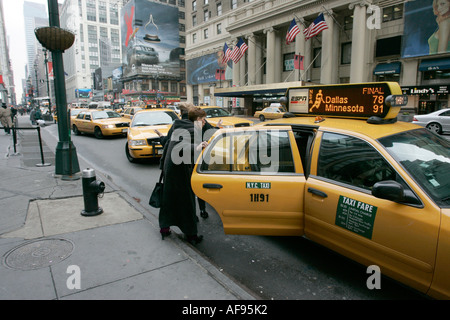 Weiße Passagiere mittleren Alters verlassen am kalten Tag die gelbe Kabinentür am Taxistand auf der 7th Avenue vor dem madison Square Garden New york City usa Stockfoto