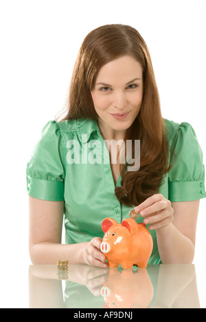 Junge Frau, Münze ins Sparschwein, Nahaufnahme Stockfoto