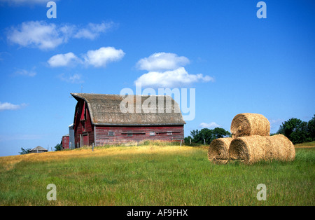 Eine alte Farm und rote Scheune auf eine Weizenfarm in den Great Plains mit Heuballen, Saskatchewan, Kanada. Stockfoto