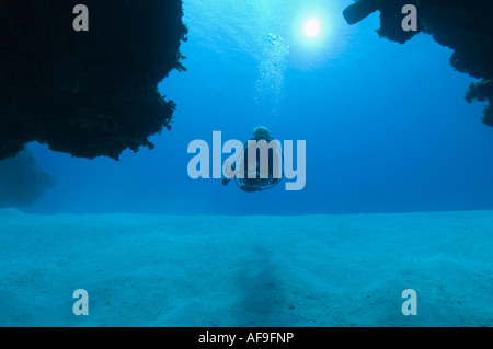 Ein Taucher Sihouetted draußen schwimmen durch mit der Sonne im Hintergrund auf einem Riff in Little Cayman Stockfoto