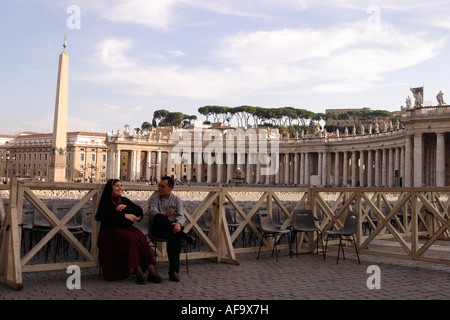 Eine Nonne und ein Laie Chat in St. Petersplatz mit dem Obelisken aus dem Zirkus von Nero im Hintergrund. Stockfoto