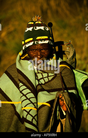 Porträt eines bärtigen Basotho-Mannes in eine Decke gehüllt, trägt eine Wollmütze und hält eine Metall-Knopf-Kerrie über seine Schulter Stockfoto