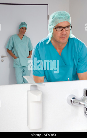 Chirurg, waschen seine Hände, weibliche Chirurg im Hintergrund Stockfoto