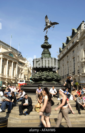 Touristen sitzen auf den Stufen rund um die Bronze Statue des Eros, Piccadilly Circus, London, England. 1893 errichtete Denkmal Stockfoto