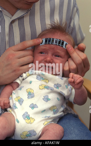 Baby mit seiner Temperatur mit einem Thermometerstreifen aufgenommen Stockfoto