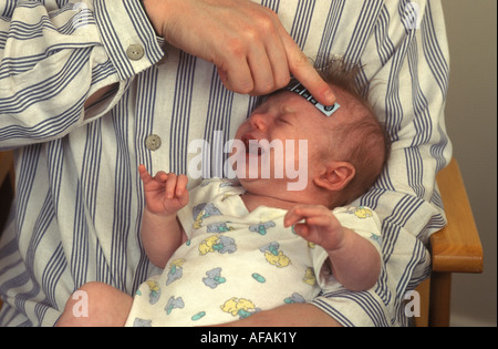 Baby mit seiner Temperatur mit einem Thermometerstreifen aufgenommen Stockfoto