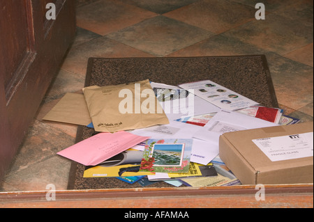 ein Berg von Post liegen auf eine Fußmatte, die in den Briefkasten geschoben worden Stockfoto