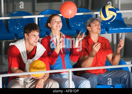 Junge Leute sitzen auf der Tribüne, Ball werfen Stockfoto