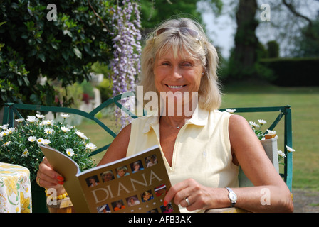 Frau mittleren Alters, entspannen und lesen im Garten, Berkshire, England, Vereinigtes Königreich Stockfoto
