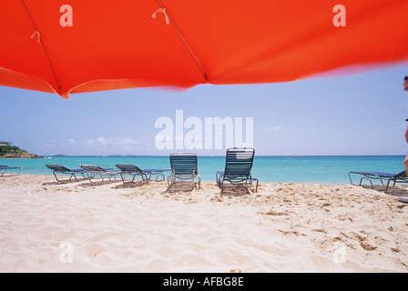 Zwei blaue einladenden Liegestühlen unter mehreren unter einem hellen roten Sonnenschirm in St Thomas U Jungferninseln Stockfoto