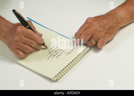Die Hände eines 65 Jahre alten Menschen mit rheumatoider Arthritis während des Schreibens einer To-Do Liste Foto von JBCN Stockfoto