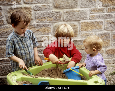 Kleine Kinder spielen mit einem Kunststoff Spaten und Containern in einem Sand Tablett Stockfoto